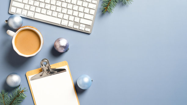 平躺圣诞家庭办公书桌与松枝，键盘，咖啡杯，圣诞装饰在柔和的蓝色背景。舒适，hygge，北欧风格。图片下载