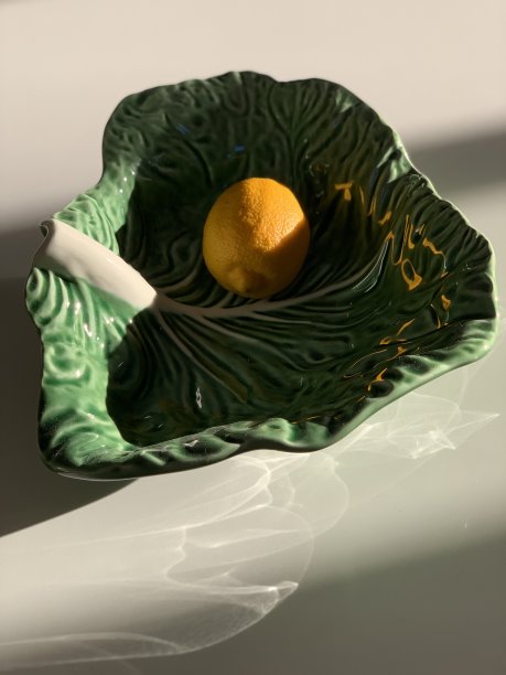 卷心菜叶形状的葡萄牙瓷杯里装着黄色柠檬图片下载