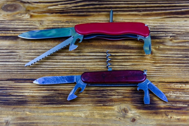 木制背景上放着两把展开的红色万能小刀图片下载