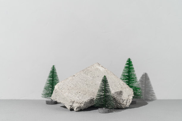 概念节日贺卡与时髦的石头讲台和三棵微型圣诞树在灰色背景图片下载