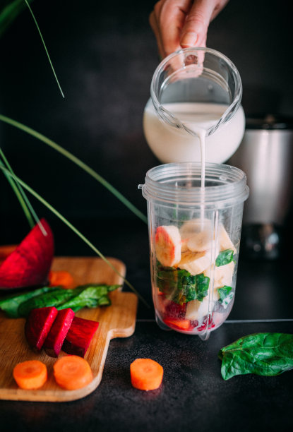 一位妇女用手将牛奶倒进搅拌机图片下载