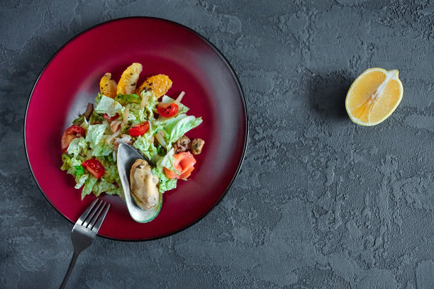 海鲜沙拉与柑橘在一个圆形盘子在灰色纹理的背景图片下载