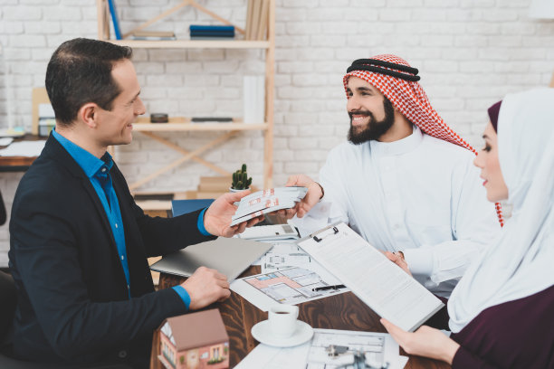 阿拉伯成年男子和戴着头巾的阿拉伯女子为房地产经纪人服务付费。房地产服务。图片下载