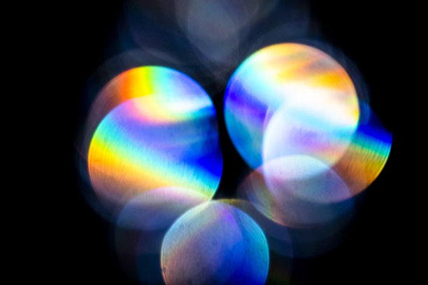 镜头光晕，散景灯。玻璃、钻石、水晶的反光。散焦的七彩彩虹光漏，光线在黑色的背景图片下载