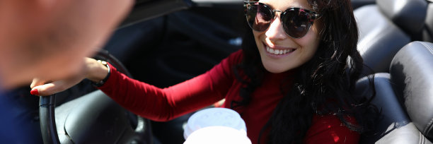 坐在车里的女人手里拿着咖啡，面带微笑，旁边是男人。图片下载