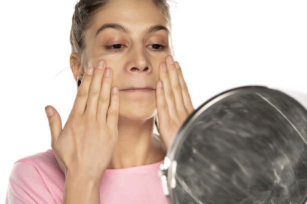 年轻女子在白色背景上涂面霜图片下载