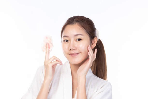 迷人的美丽年轻的亚洲女子清洁皮肤与卸妆棉在白色的背景。图片下载