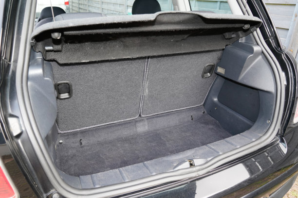在现代小型黑色城市轿车中打开后面的黑色小行李箱图片下载