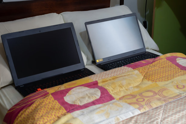 床上有两台黑色笔记本电脑和枕头，是生活方式和家庭办公概念图片下载