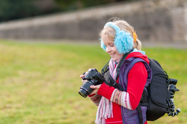 一个快乐的小女孩拿着照相机，戴着蓝色的耳套图片下载