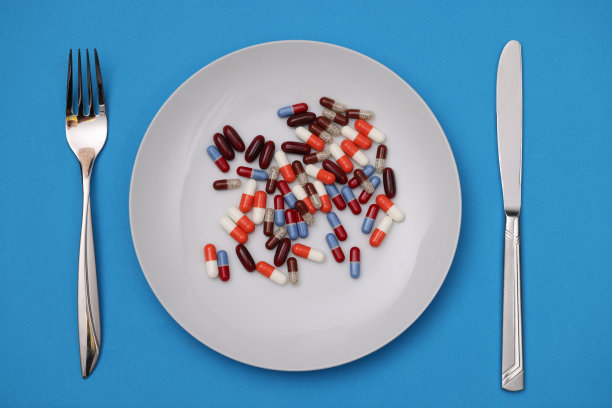 许多彩色胶囊和躺在盘子上用叉和刀特写图片下载