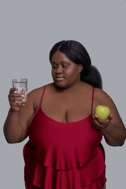 黑皮肤的女人拿着一个苹果和一杯水图片下载