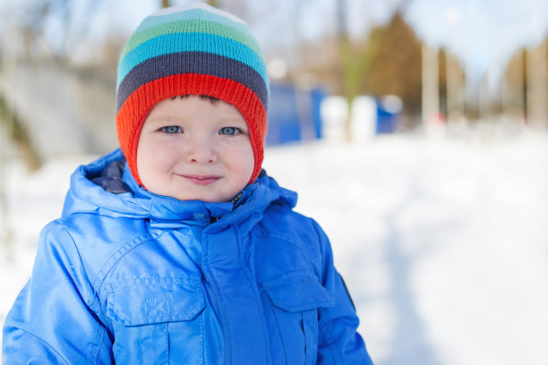 冬天，小孩子走在下雪的街上。一个穿着暖和的孩子在冬天走在街上图片下载