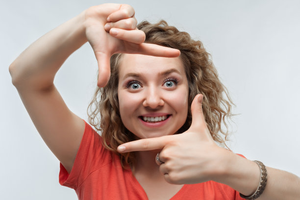 有趣的女人微笑的照片，用手指做相框。人的情绪、表情概念图片下载