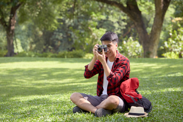 快乐的亚洲人背包客坐在草地上在一个夏天的一天图片下载