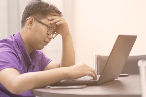 亚洲商务人士在办公室的木桌上放着笔记本电脑和纸张，对工作感到压力很大。亚洲男人在工作不成功时很担心。图片下载