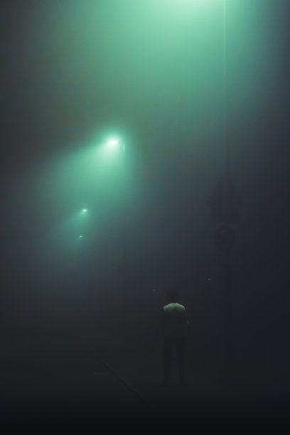 少年在空无一人的街道上等待，被街灯照亮的雾气所笼罩图片下载