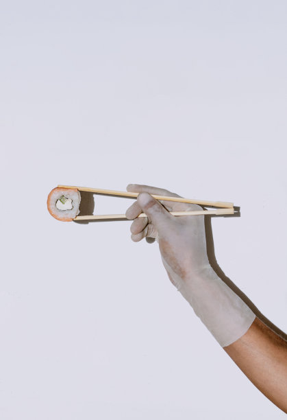 用橡胶手套把寿司和筷子放在白色的背景上。寿司菜单。图片下载