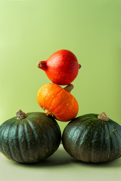 堆叠的绿色和橙色南瓜在石灰绿色的背景图片下载