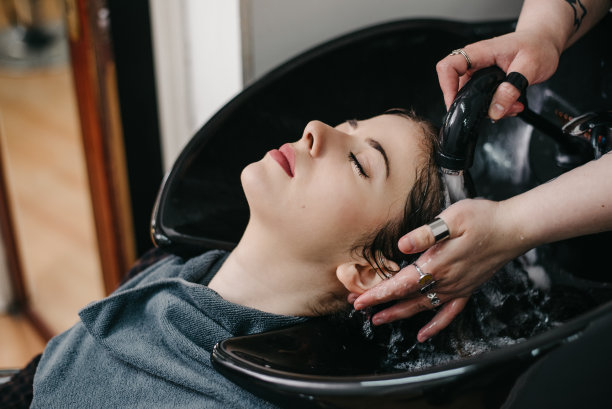 美发师在美容院为年轻女子洗头图片下载