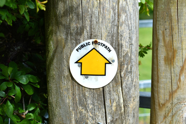 靠近公共人行道的木杆上的黄色箭头标志图片下载