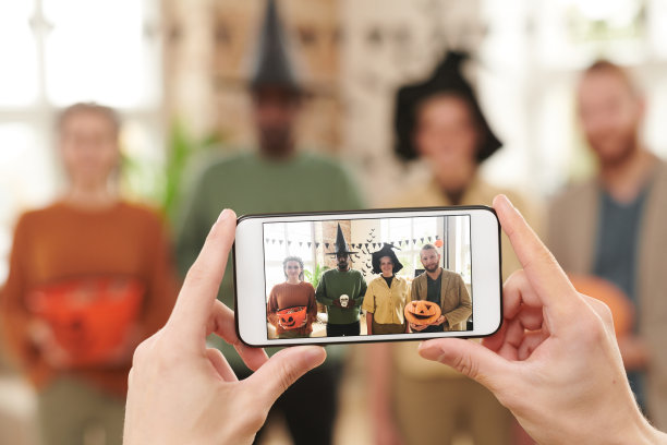 手用智能手机拍摄人们在万圣节派对上的装饰，照片的社交媒体图片下载