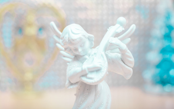 一个带着银光片的雪白天使在蓝色云杉和金色的心的背景下弹奏着班卓琴。高的关键。圣诞节的照片。图片下载