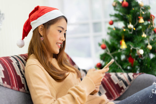 近距离年轻的亚洲女性拿着智能手机阅读社交媒体网页上的新闻或检查市场网站上的折扣促销购物在圣诞节庆祝节日的概念图片下载