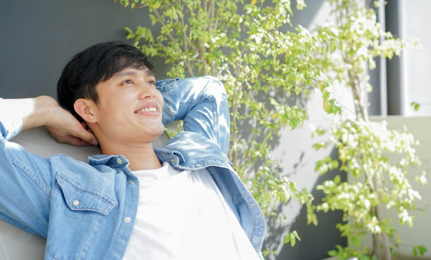 近距离观察年轻的亚洲男子躺在家门口花园的沙发上放松身心，感受正念和生活方式的概念图片下载
