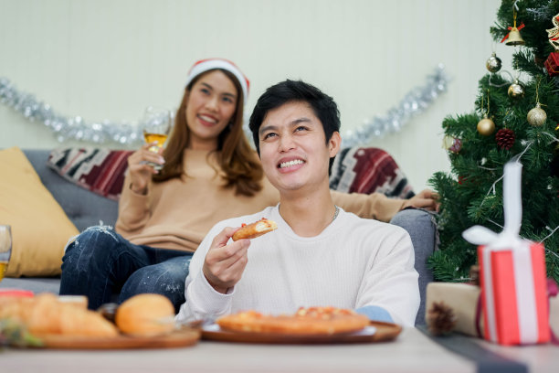 近距离情侣吃披萨甜点和喝葡萄酒和看电视娱乐媒体一起在家里为圣诞节和假日的生活方式概念图片下载