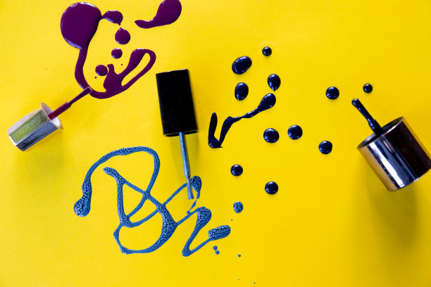 紫色的指甲油在黄色的背景上凝固。蓝色和紫色油漆飞溅。漂亮的指甲油图案。指甲油滴。图片下载