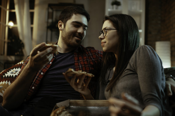 幸福的夫妇在家里吃披萨。图片下载