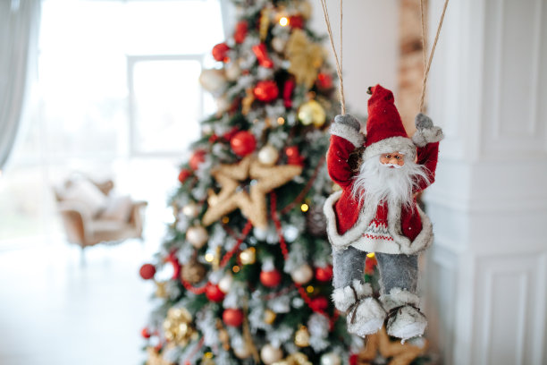 圣诞老人的玩具降落伞带来礼物在红色的圣诞树散焦的背景。大Copyspace概念新年横幅，海报。图片下载