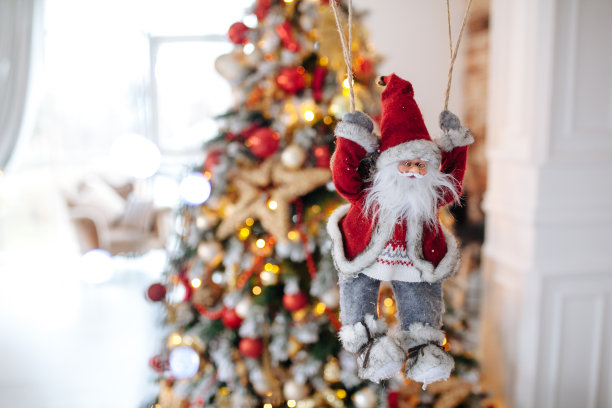 圣诞老人玩具降落伞带来礼物在红色圣诞树散景背景。大文案空间概念新年横幅、海报。图片下载