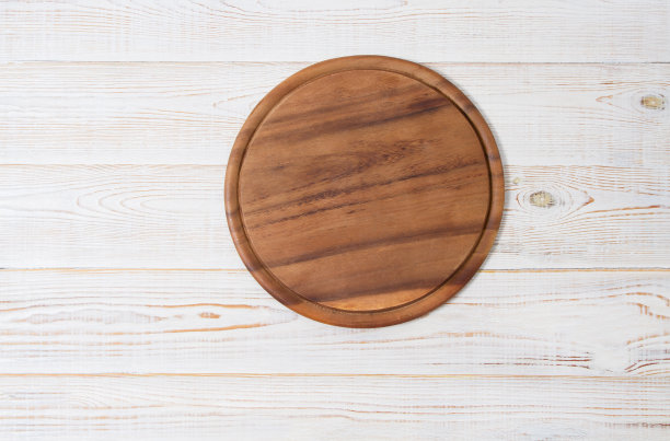厨房白色木制餐桌背景上的圆形披萨砧板。俯视图和复制空间。图片下载