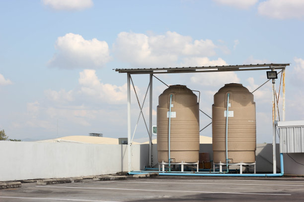 在蓝天白云的建筑屋顶上设置了一个水箱。供饮用或使用的水箱。图片下载