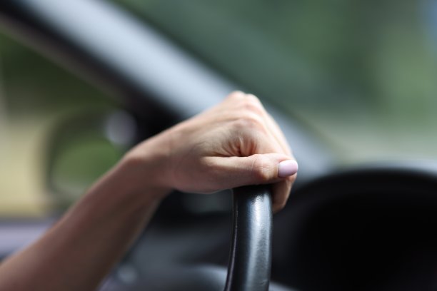 女性手握真皮方向盘。图片下载