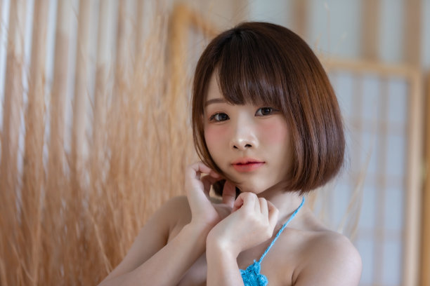 年轻漂亮的亚洲女人的肖像穿着蓝色比基尼在她的房间。图片下载