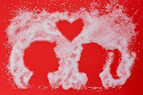 白糖在红色的背景与情侣的剪影在爱情。新潮简约的情人节概念，婚礼，爱情，真实的感觉，传统的异性情侣。副本的空间。图片下载