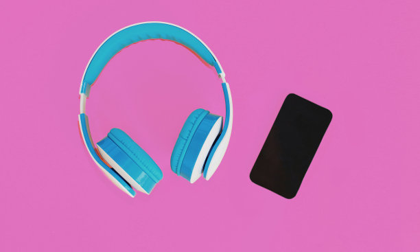 近距离蓝色耳机和智能手机在彩色的粉红色背景图片下载