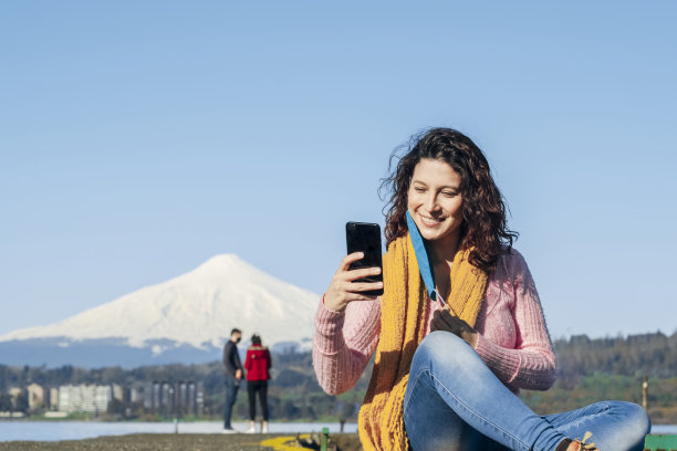 一名年轻女子摘下口罩，用手机自拍。图片下载