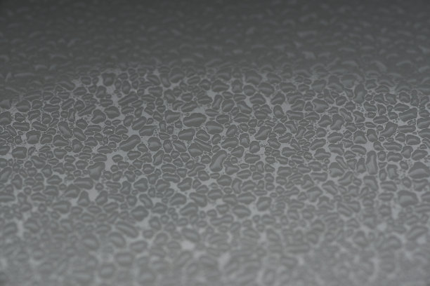 以黑白细条纹为背景的金属表面上的液体图片下载