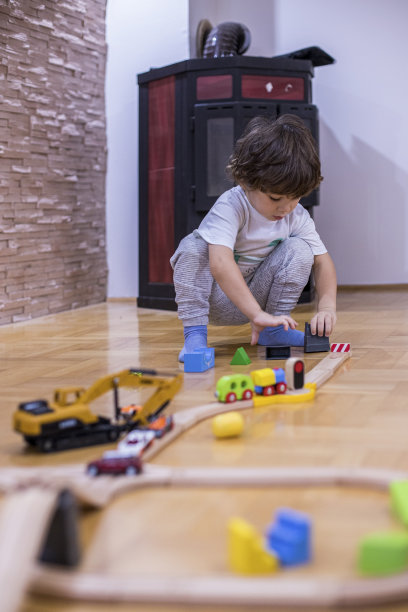 漂亮的小男孩在玩火车玩具。图片下载