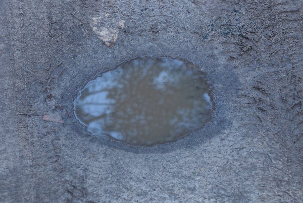 灰色的地面上有褐色脏水的大水坑图片下载
