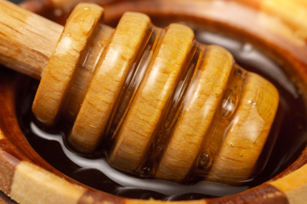 糖糊或美容蜡从木勺流出来。蜂蜜从勺子里滴下来。宏观照片图片下载