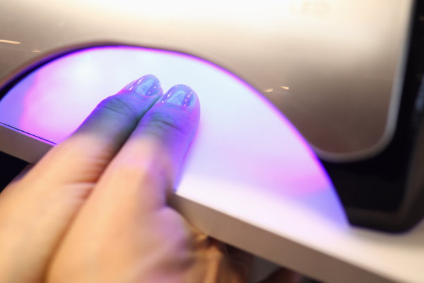 女人做美甲和干指甲在紫外线灯特写。图片下载