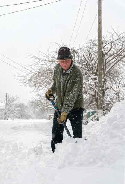 一个人用铲子清理雪地上的轨道图片下载