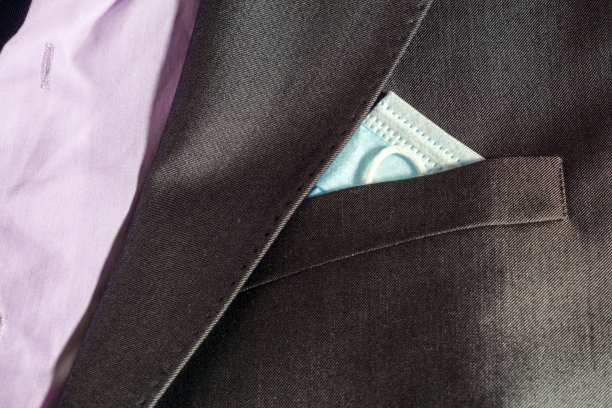 的概念。Covid时尚。装在夹克口袋里的防护口罩。图片下载