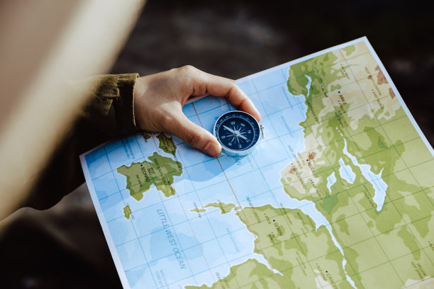 女人的手看地图和指南针检查她的位置。图片下载