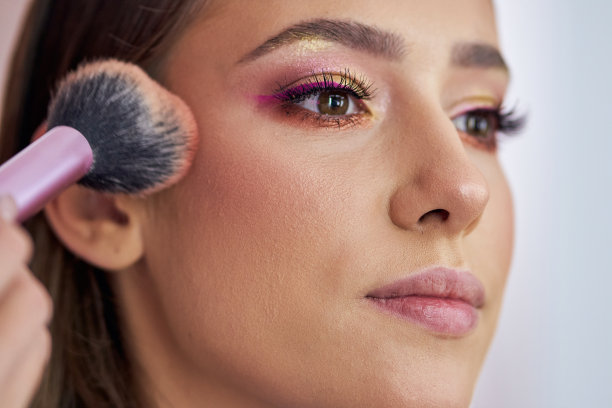 熟练的化妆师在顾客的骨头上涂铜以强调轮廓图片下载